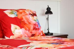 GorsselGastenverblijf Kleinkamperfoelie的红色的床,带花枕和灯