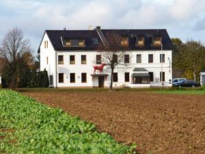 都伦-埃菲尔Hotel-Restaurant Rotes Einhorn Düren *** Superior的黑色屋顶和田野的白色房子
