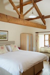 GrantleyDallow Hall Barns的卧室配有一张带木梁的白色大床