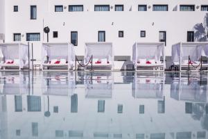 普拉亚登博萨米格霍恩伊维萨套房水疗酒店的坐在建筑物前水面上的四把椅子