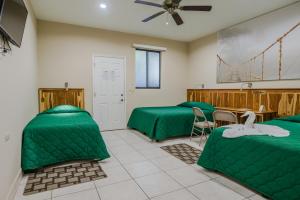 格拉纳达Hotel Los Chilamates的客房设有两张绿色的床和一张桌子