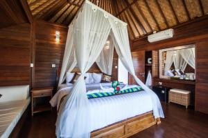 蓝梦岛隆堡冈古邦小屋度假村的一间卧室配有一张带天蓬的白色床