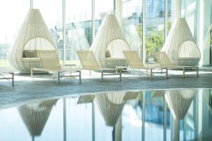 克尔门德Mjus Resort & Thermal Park的水中反射的建筑物中的一排椅子