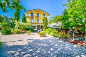 西尔米奥奈瑞尔酒店的庭院里种满树木和鲜花的黄色建筑