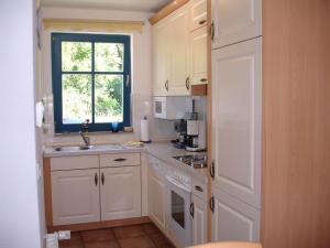 坡瑟利特兹Puddemin Haus Malve 2的一间小厨房,配有白色的橱柜和窗户