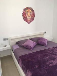 托雷帕切科Villa Mar menor Golf的一张带紫色床单的床和墙上的狮子照片