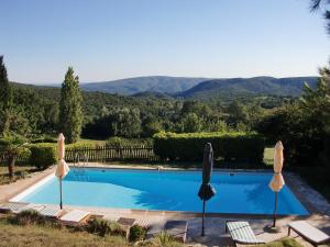 Saint-Montan帕查拉住宿加早餐旅馆的一个带两把遮阳伞和椅子的游泳池