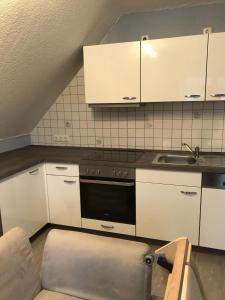 比苏姆Haus-Norderpiep的厨房配有白色橱柜、炉灶和水槽。