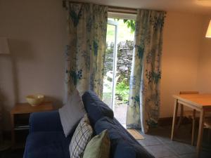 ClachanOban Seil Farm The Bothy的客厅设有蓝色的沙发和滑动玻璃门