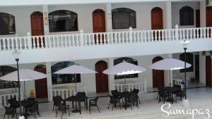 梅尔加Suite Sumapaz Hotel的一座配有桌椅和白色遮阳伞的建筑