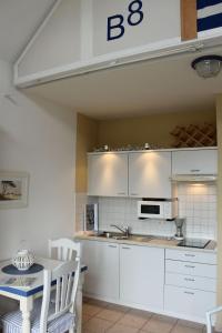 奥斯特巴德里克Ferienwohnung-Meeresblick-Rerik的厨房配有白色橱柜和桌椅