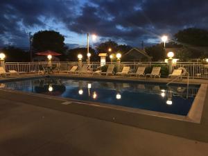 五月岬郡Cape Harbor Motor Inn的夜间游泳池,配有椅子和灯