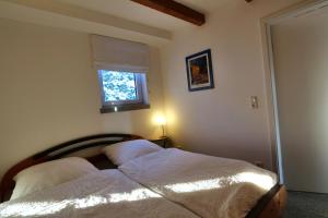 基彭海姆Gesindehaus Charis的一间卧室配有一张带白色床单的床和一扇窗户。