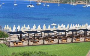 苏尼翁爱琴海岸酒店的水边的度假胜地,配有椅子和遮阳伞