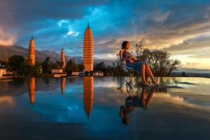 大理Dali Rong lu Hotel的坐在水塘旁椅子上的女人