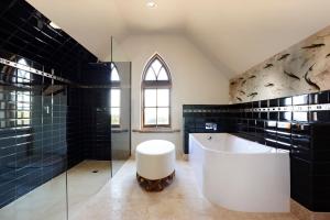 Fish CreekThe Church House Gourmet Retreat的浴室设有白色浴缸和黑色瓷砖。