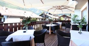 平佐洛皇家奥林匹克酒店的甲板上设有桌子和遮阳伞的餐厅