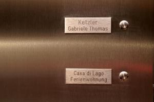 海因斯贝格Ferienwohnung Casa Di Lago的虎弹壳门上的两个标志和一个膝盖型的箱子
