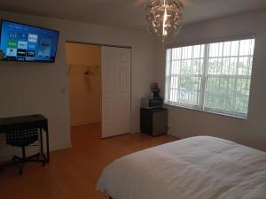 黎明城萨瓦草度假屋的卧室配有白色的床和墙上的电视。