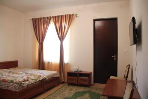 古达乌塔АМРАПХА的一间卧室设有一张床、一个窗口和一台电视
