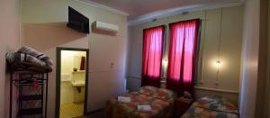 卡尔古利卡尔古利宫殿酒店的小房间设有床和红色窗帘的窗户