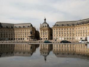 波尔多Appart Cozy / Quartier St Pierre的一座有两座大建筑的城市,在水中反射