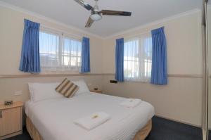凯阿玛肯达勒斯海滩假日公园的卧室配有一张带蓝色窗帘的大型白色床