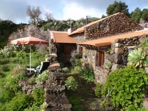 El Pinar del HierroCasa rural La Jarita的一座石头房子,上面有雨伞和一些植物