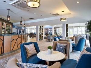 达文特里Staverton Park Hotel & Golf Club的大堂设有蓝色桌椅,酒吧