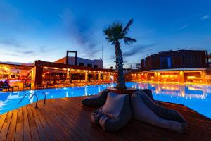 卡拉马塔伊利特城市度假酒店的一座棕榈树游泳池,毗邻一座建筑
