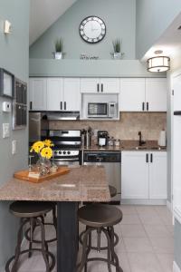 蓝山蓝山山畔复式公寓的厨房配有白色橱柜和带凳子的台面