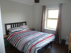 杜林Mary's Meadow的一间卧室配有带条纹棉被的床和窗户