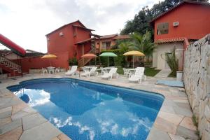 皮雷诺波利斯Pousada Recanto的房屋旁的游泳池配有椅子和遮阳伞