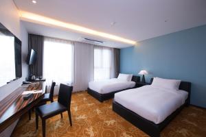 济州市利奥酒店的酒店客房设有两张床、一张桌子和一台电视。