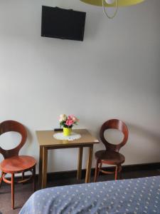 Breuillet努沃莫德酒店的一张桌子、三把椅子和一张桌子,上面有鲜花