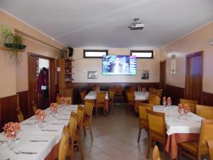 LimosanoHotel Coste Del Lago的一间带桌椅和电视的用餐室