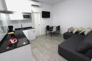 马德里阿尔玛套房公寓的一间带黑色沙发的客厅和一间厨房