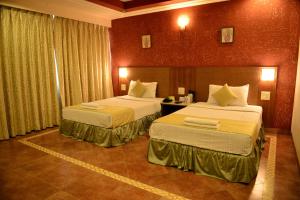 马尔冈Goa Woodlands Hotel的一间酒店客房,房间内设有两张床