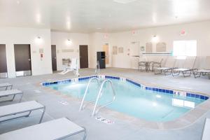 史普林维尔Microtel Inn & Suites by Wyndham Springville的一个带桌椅的房间的游泳池
