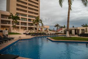 马萨特兰Ocean View Beach Hotel的一座棕榈树游泳池和一座建筑