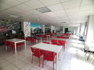 中坜长缇都会商务旅馆的用餐室配有桌子和红色椅子