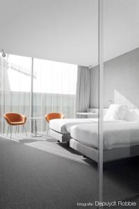 科特赖克D酒店的一间卧室配有两张床和一张桌子及椅子