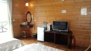 仁爱乡清境小太阳景观木屋 的一间卧室设有木墙、电视和冰箱。