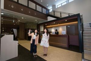 富士河口湖Mt.Fuji Cabin & Lounge Highland Station Inn (Capsule Hotel)的两名妇女站在大楼的大厅里