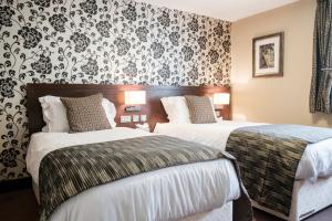 Clanfield富勒汉普郡酒店的两张位于酒店客房的床铺,配有花卉壁纸