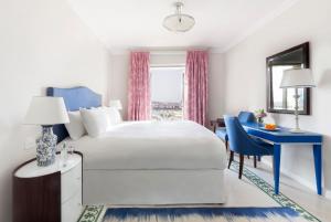 瓦莱塔The Phoenicia Malta的卧室配有白色的床和蓝色的书桌