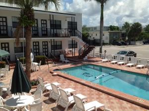 劳德代尔堡那波利贝勒马酒店的一个带白色椅子的游泳池和一间酒店