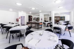 马里纳迪马萨拉布索拉酒店的用餐室配有白色桌子和黑色椅子