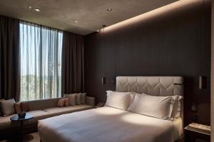 米兰Hotel VIU Milan, a Member of Design Hotels的酒店客房设有一张大床和一张沙发。