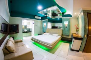 福塔莱萨Netuno Motel (Adults Only)的一间卧室配有一张床、一张沙发和一台电视。